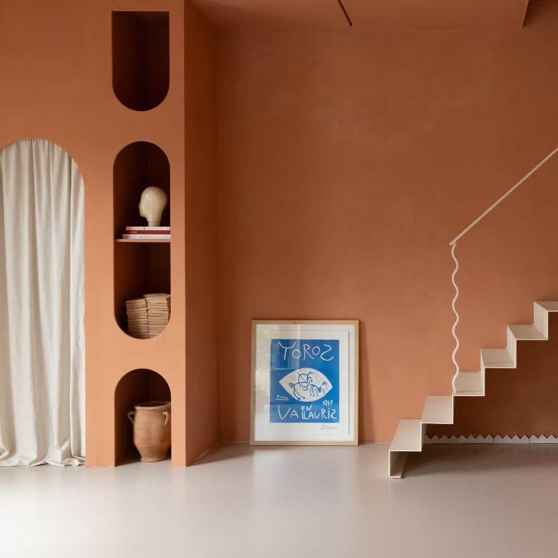 Terracotta wand met nissen en een witte trap