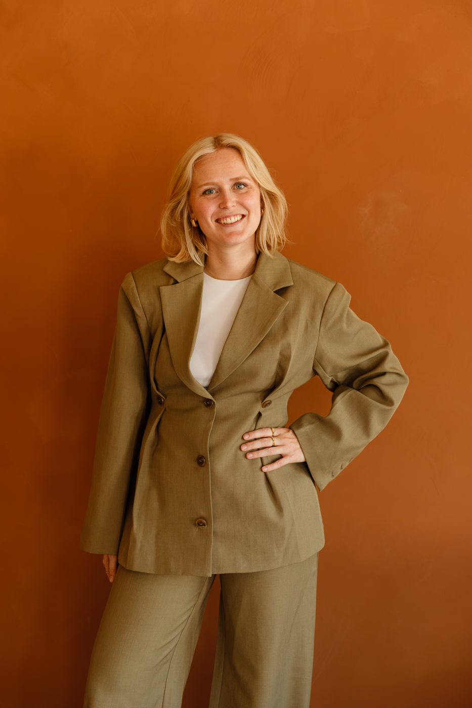 Jackie in een groen pak voor een terracotta muur